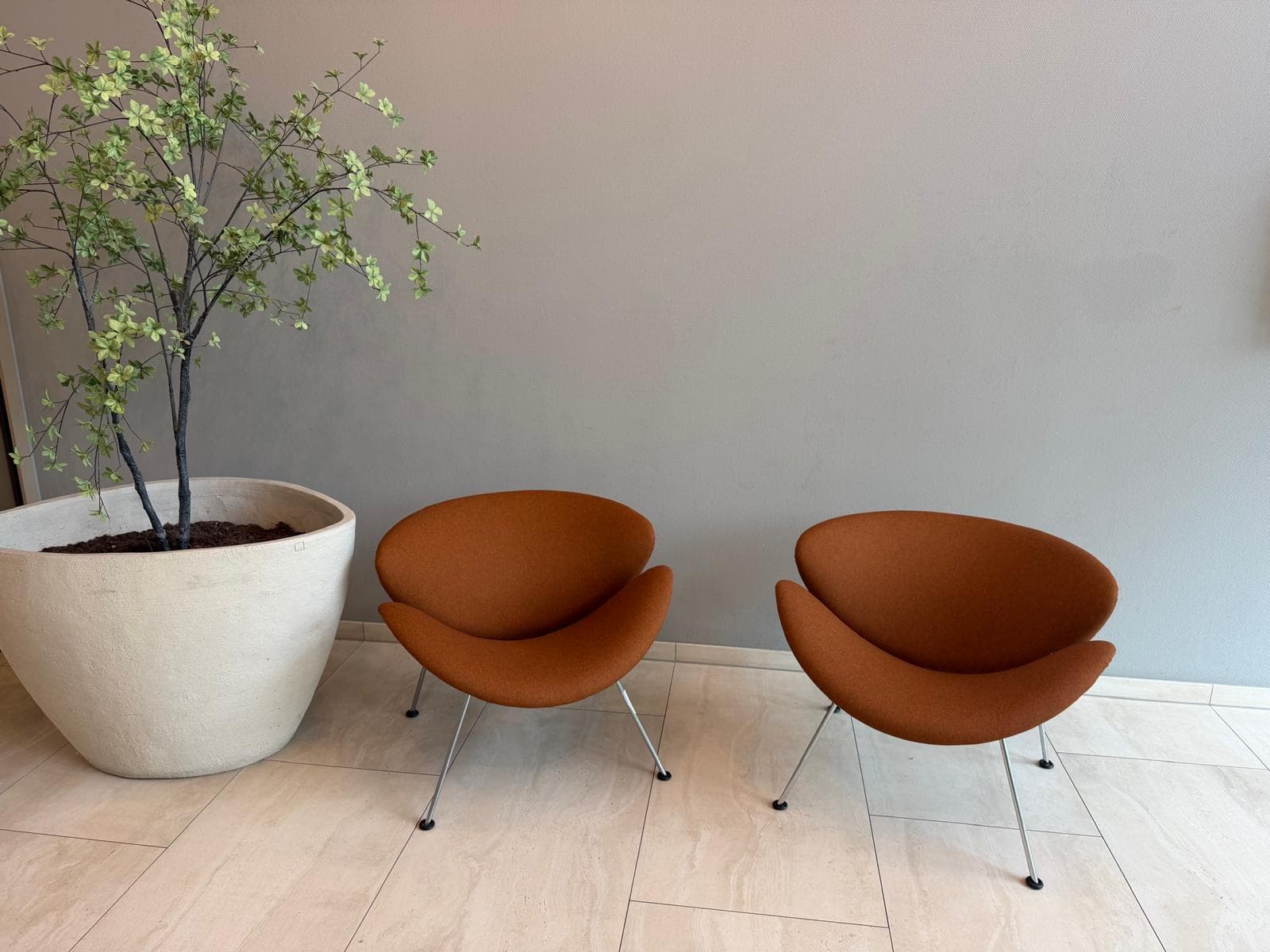 Twee gestoffeerde oranje designfauteuils in een licht interieur