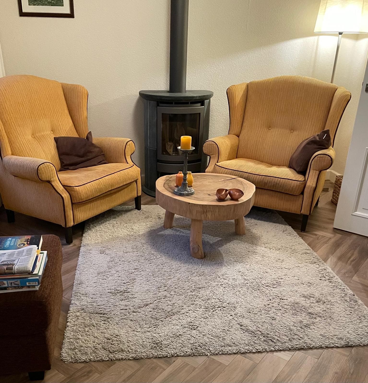 Twee gestoffeerde fauteuils in een warme woonkamer met houtkachel