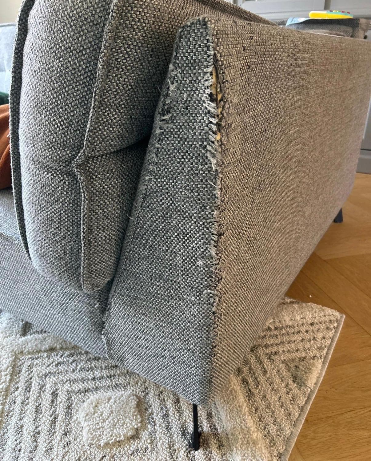 Hoek van een bank vóór herstel — beschadigde en versleten bekleding